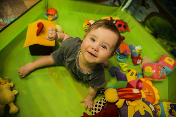 Fototapeta na wymiar smiling boy (7 month old) sits in a green floor, laughs, plays with toys.