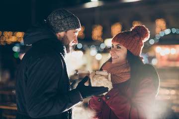Photo of two charming people with hot tea beverage in hands celebrating x-mas eve in magic outdoors atmosphere wearing warm jackets