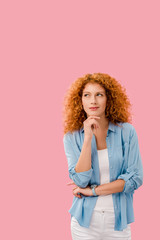 attractive pensive redhead woman isolated on pink