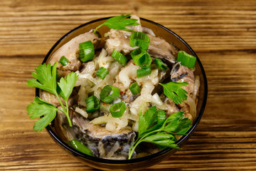 Marinated carp in glass bowl on wooden table