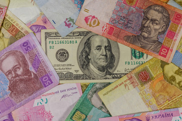 One hundred dollar bill on a background of ukrainian hryvnia banknotes