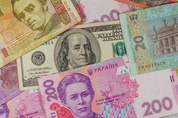 One hundred dollar bill on a background of ukrainian hryvnia banknotes