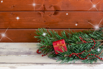 Pine branches, beads and red gift box on wooden background. Selective focus on gift box.  Christmas background. View with copy space.