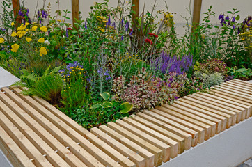 A raised flower border with bench seating in a public urban garden space