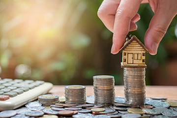 hand put house model on money coins saving for concept investment mortgage fund finance and home...
