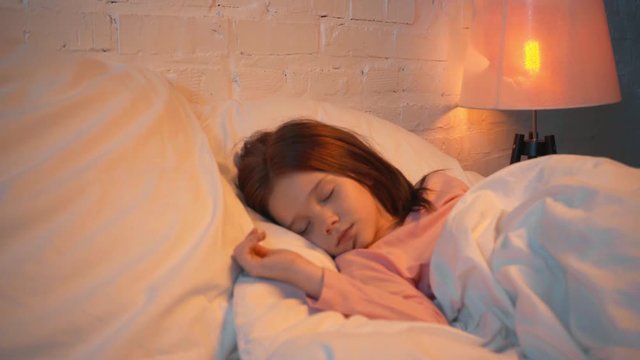 child sleeping in white bed at night