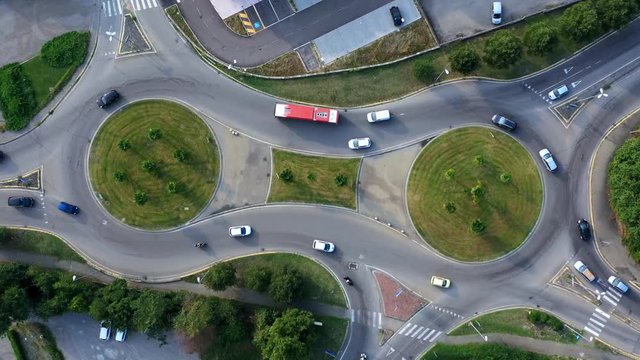 Aerial view of car traffic around an eight-shaped roundabout. Roundabout aerial top down view footage from above with vehicles circling around the traffic circle lane
