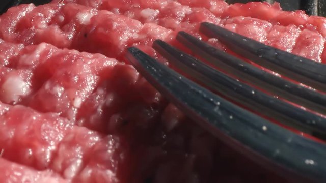 Chef cook in black gloves forms a cutlet for cooking with a fork on the cutlet, the main ingredient for a burger, top view close-up