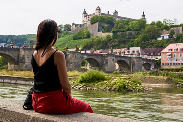 Young girl by the river contemplating the beautiful views towards the old bridge and the fortress...