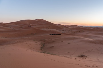 Fototapeta na wymiar Gorgeous and scenic desert scene with the moon crescent high above beautiful sand dunes Erg Chebbi, Morocco, Merzouga