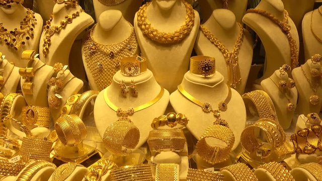 Precious Gold Necklaces, Earrings And Bracelets On Rotating Stands. Many Gold Jewelry With Precious Stones In A Jewelry Store Window.