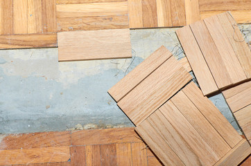 Renovation of a damaged parquet while fixing new wooden tiles instead of old