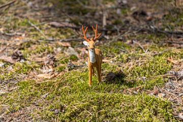 Obraz premium Little Toy Deer in a Green Forest on a Sunny Day