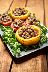 Peppers stuffed with champignons with lettuce on wooden table