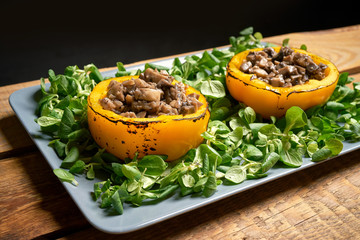 Peppers stuffed with champignons with lettuce on wooden table