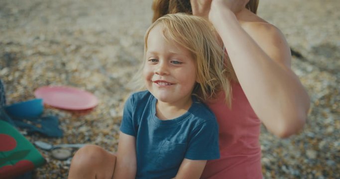 Happy little toddler enjoying picnic on the beach with mother and grandmother