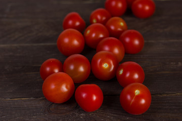 Red cherry tomatoes on a dark wooden background.