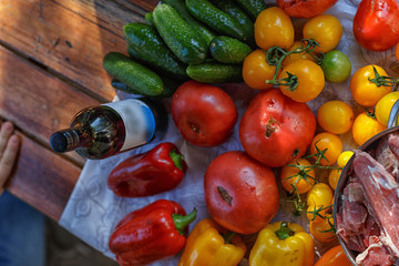 tomatoes, cucumbers and sweet peppers on a transparent oilcloth on a wooden table