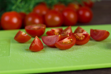 Cherry tomatoes on sliced with a sprig of dill on a green cutting board.