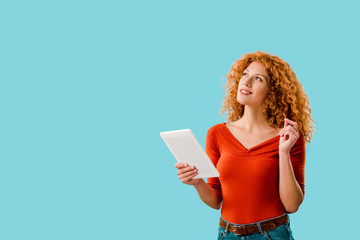 beautiful dreamy woman using digital tablet isolated on blue