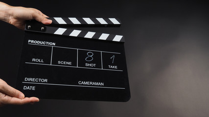 Fototapeta na wymiar Hand is holding Black clap board or movie slate use in video production , movie ,film, cinema industry on black background.It have write in number.