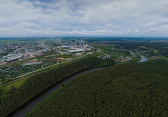 Sukhoy Log city, Pyshma river, dark forest and cement factory. Russia, Aerial, cloudu day