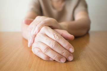 Parkinson's disease symptoms. Close up of tremor (shaking) hands of Middle-aged women patient on...