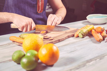 Young chef in kitchen holding knife and preparing dinner. Food concept.