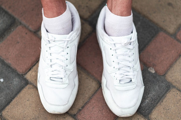 white sneakers on a guy on a tile one