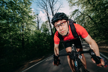 a professional cyclist in a helmet rides fast along a forest road