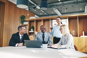 Diverse group of businesspeople laughing together around an offi