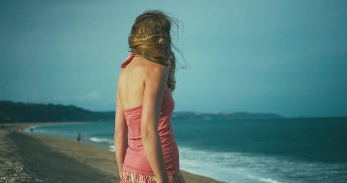 Young woman standing on the beach turns to look