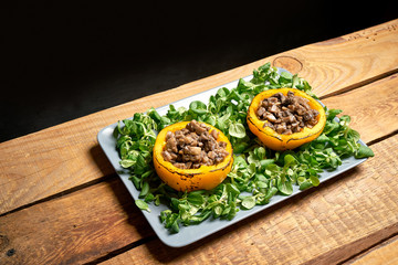 Peppers stuffed with champignons with lettuce on wooden table