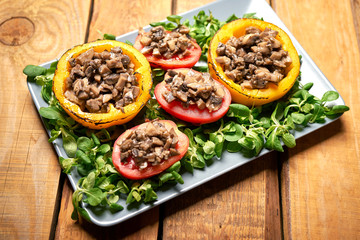 Peppers stuffed with champignons with lettuce on wooden table