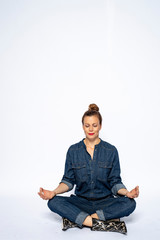 Beautyful woman in Studio in Modern Jeans outfit is sitting in a yoga seat