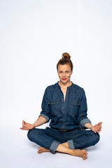 Beautyful woman in Studio in Modern Jeans outfit is sitting in a yoga seat