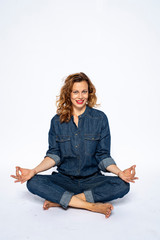 Beautyful woman in Studio in Modern Jeans outfit is sitting in a yoga seat