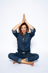Beautyful woman in Studio in Modern Jeans outfit is sitting in a yoga seat