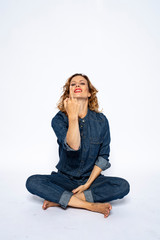 Beautyful woman in Studio in Modern Jeans outfit is sitting in a yoga seat