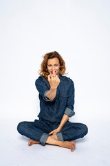 Beautyful woman in Studio in Modern Jeans outfit is sitting in a yoga seat