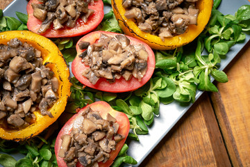 Peppers stuffed with champignons with lettuce on wooden table