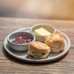 Close up shot of russian cottage cheese pancakes on a plate with jam and butter in saucers. These pancakes make a delicious dessert or a light summer meal.