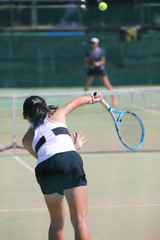 サーブを打つ女子テニスプレイヤー