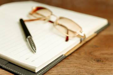 Fototapeta premium Notebook of writer and pen placed on table with vintage eyeglasses