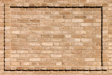 Antique wall made of scratched beige bricks, beige cement seam and beautiful rectangular frame made of bricks. Texture background