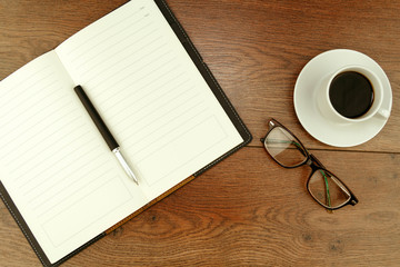Top view on business workplace. Office supplies and eyeglasses near to cup of espresso on wooden table