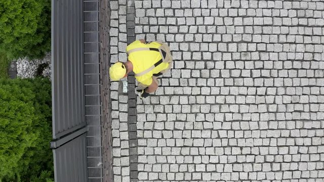 Aerial View of Construction Worker Paving Brick Driveway. Industrial Theme.