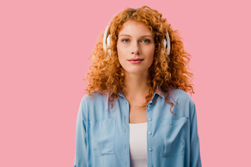 attractive redhead woman listening music in headphones, Isolated On pink