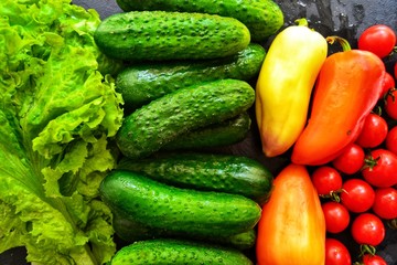 Composition with assorted fresh organic vegetables. Assorted fresh vegetables and fruits. Place for text. Cucumbers, lettuce. Food on a dark table background.