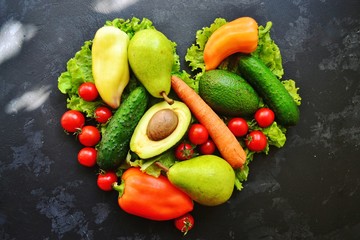 Composition with assorted fresh organic vegetables. Assorted fresh vegetables and fruits. Place for text. Cucumbers, tomatoes, pears, avocados, carrots, sweet peppers. Heart shaped vegetables.